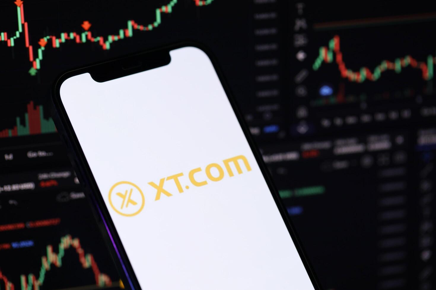 KYIV, UKRAINE - MARCH 15, 2024 XTcom logo on iPhone display screen and crypto currency value charts photo