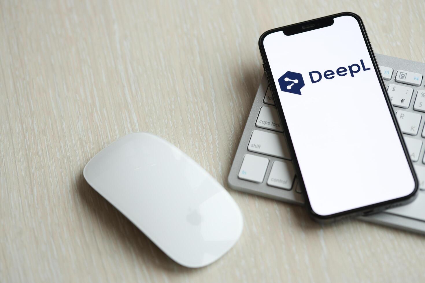 KYIV, UKRAINE - MARCH 17, 2024 DeepL logo on iPhone display screen with apple keyboard and mouse on table photo