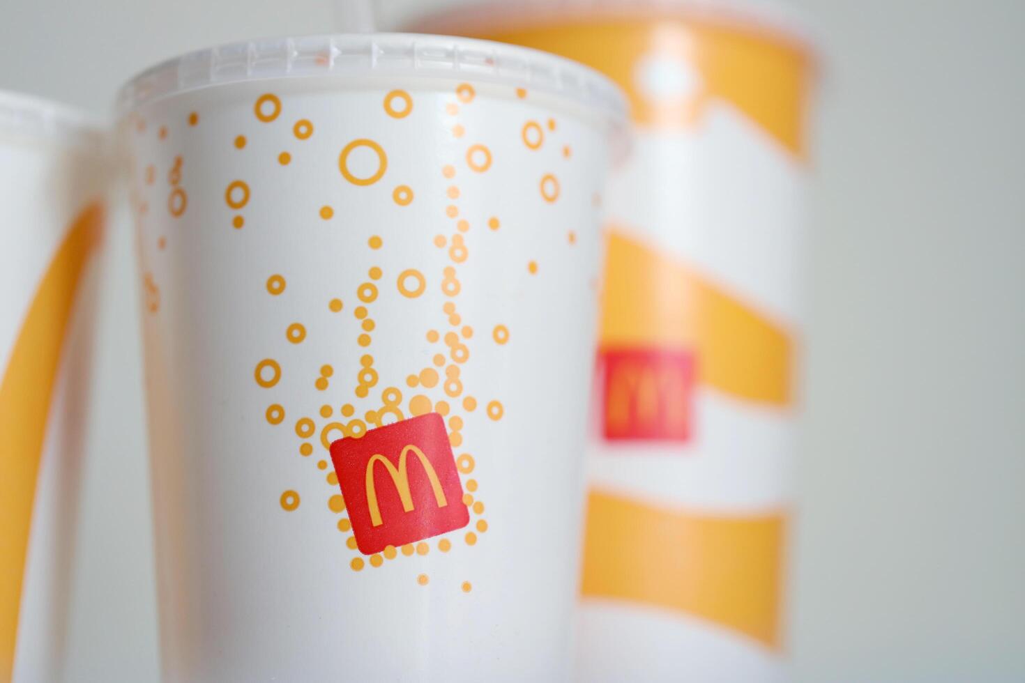 KYIV, UKRAINE - APRIL 20, 2024 Cold McDonald's drinks with company logo on grey table. Red McDonalds logotype on disposable cups photo