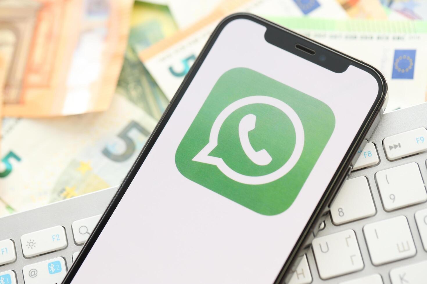 KYIV, UKRAINE - APRIL 1, 2024 Whatsapp messenger icon on smartphone screen on many euro money bills photo