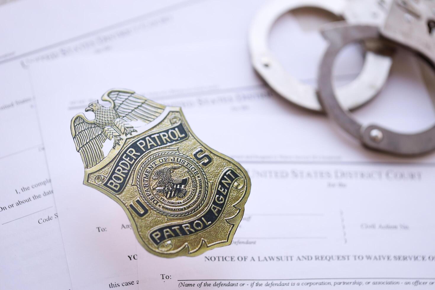 KYIV, UKRAINE - MARCH 9, 2024 US Border Patrol Agent badge with handcuffs on many US District Court warrants and complaints photo