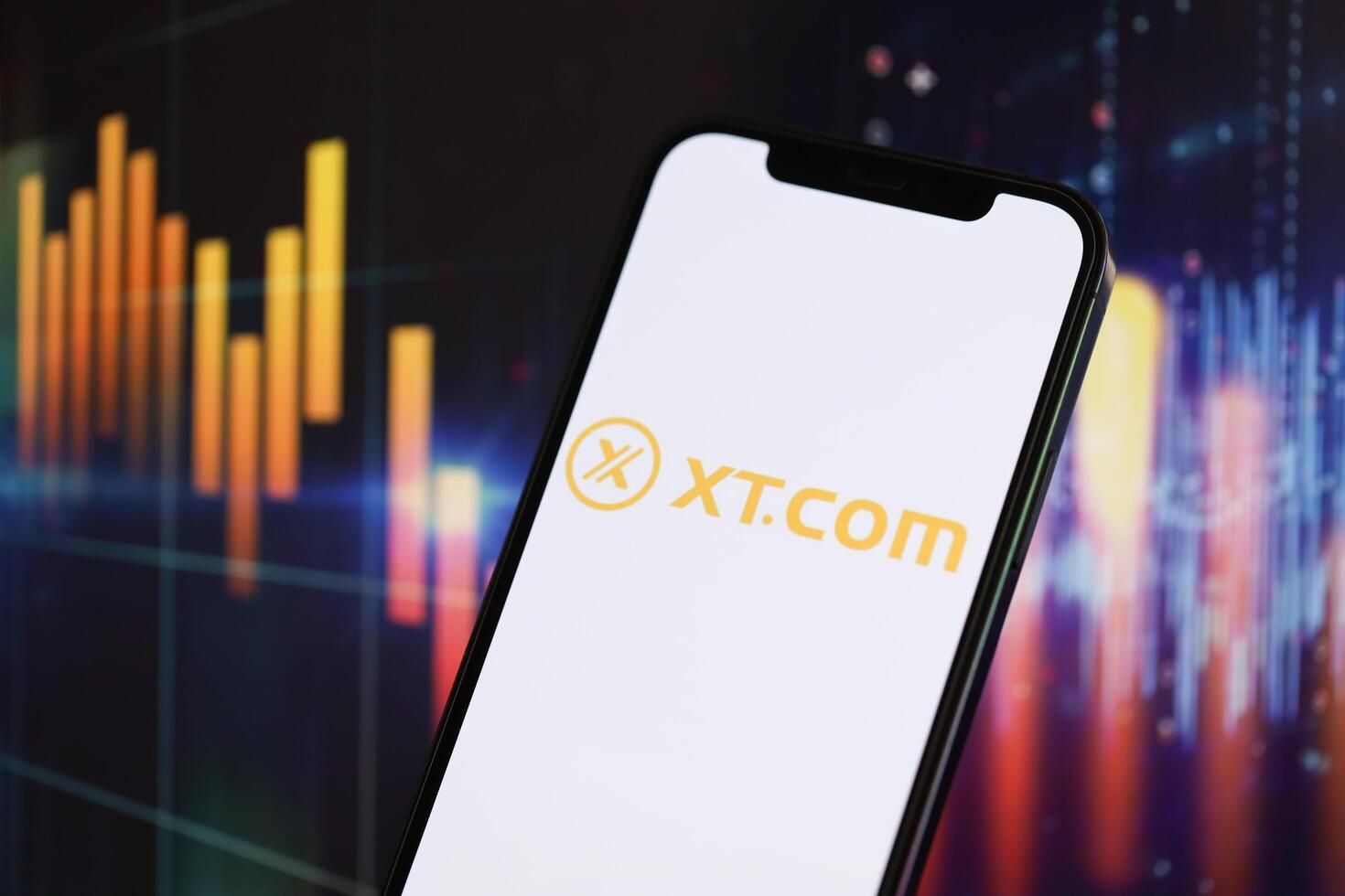 KYIV, UKRAINE - MARCH 15, 2024 XTcom logo on iPhone display screen and crypto currency value charts photo