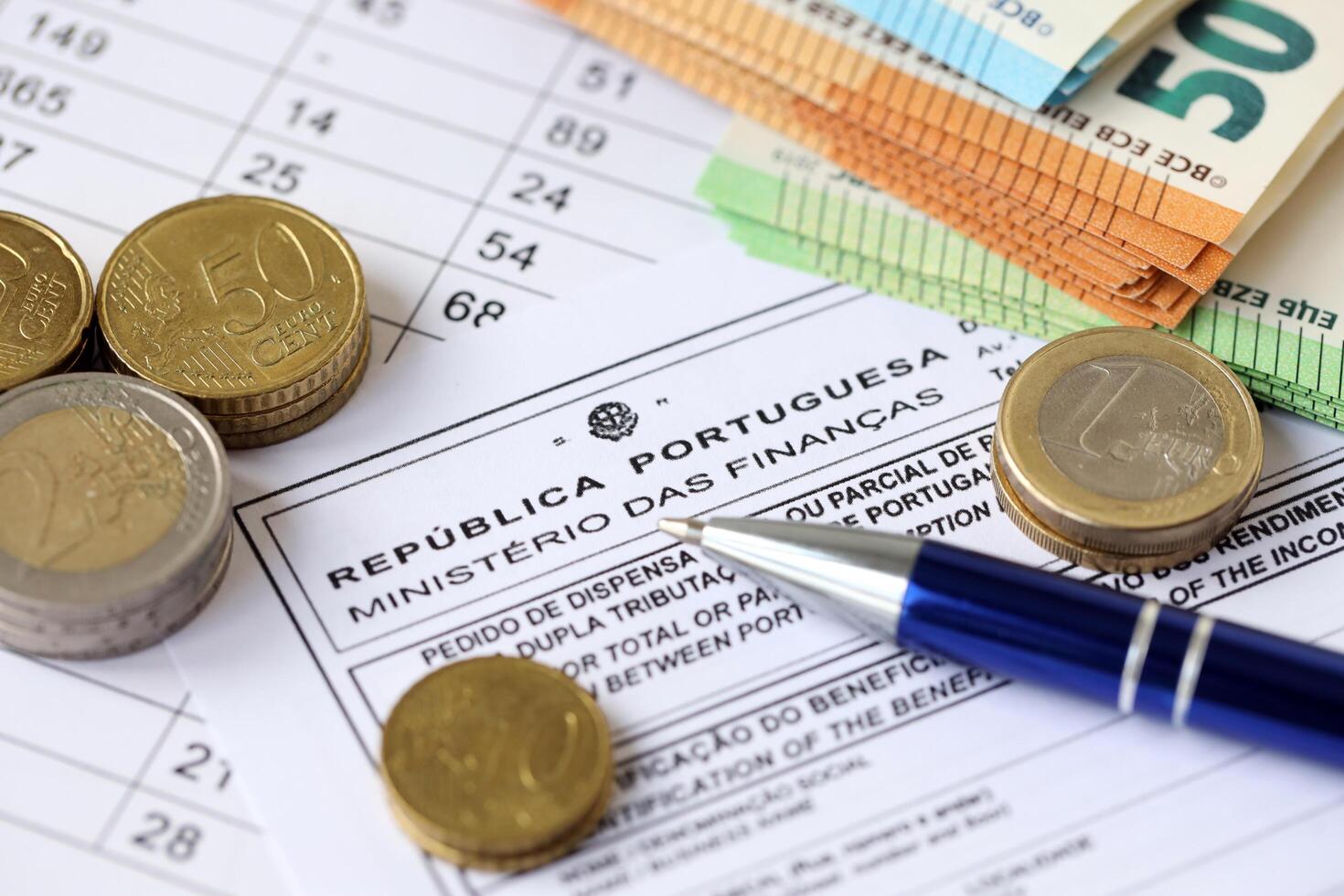 KYIV, UKRAINE - APRIL 20, 2024 Ministerio Das Financas logo from portugese blank tax form and many euro banknotes on office table photo