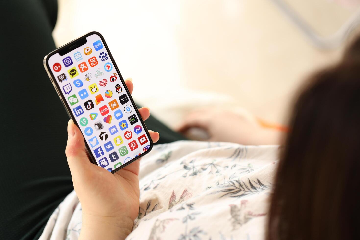 KYIV, UKRAINE - APRIL 1, 2024 Many apps icon on smartphone screen in young female hands photo
