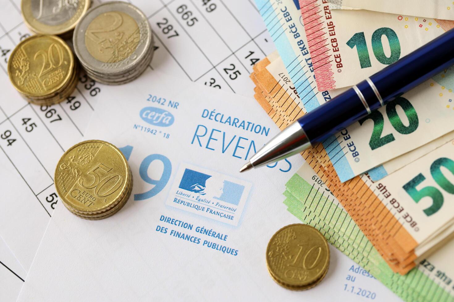 KYIV, UKRAINE - APRIL 20, 2024 Republique Francaise Cerfa logo from french blank tax form and many euro banknotes on office table photo