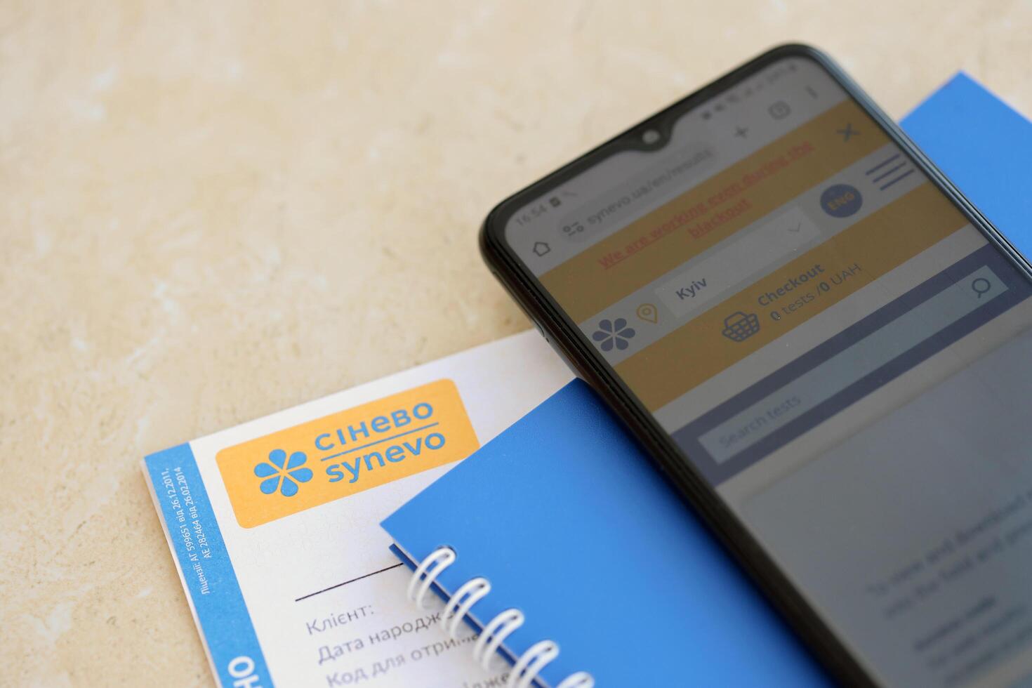 KYIV, UKRAINE - 4 MAY, 2023 Synevo medical analysis results and smartphone with synevo official website on screen photo