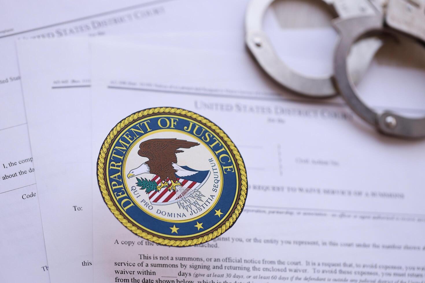 KYIV, UKRAINE - MARCH 9, 2024 US Department of Justice seal with handcuffs on many US District Court warrants and complaints photo