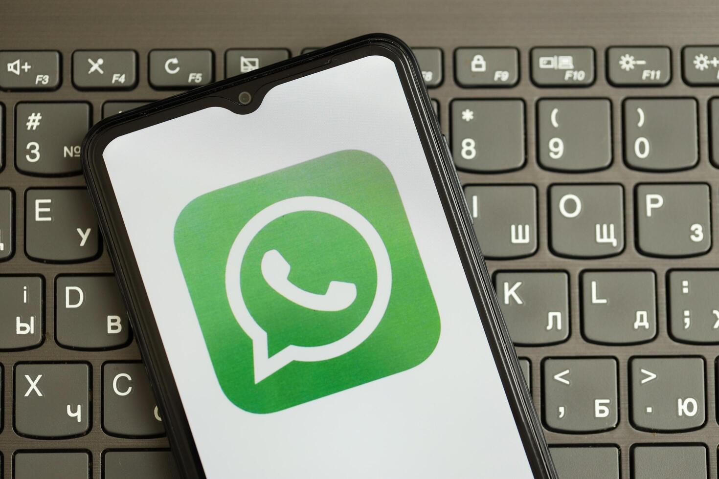 KYIV, UKRAINE - APRIL 1, 2024 Whatsapp messenger icon on smartphone screen on black keyboard photo