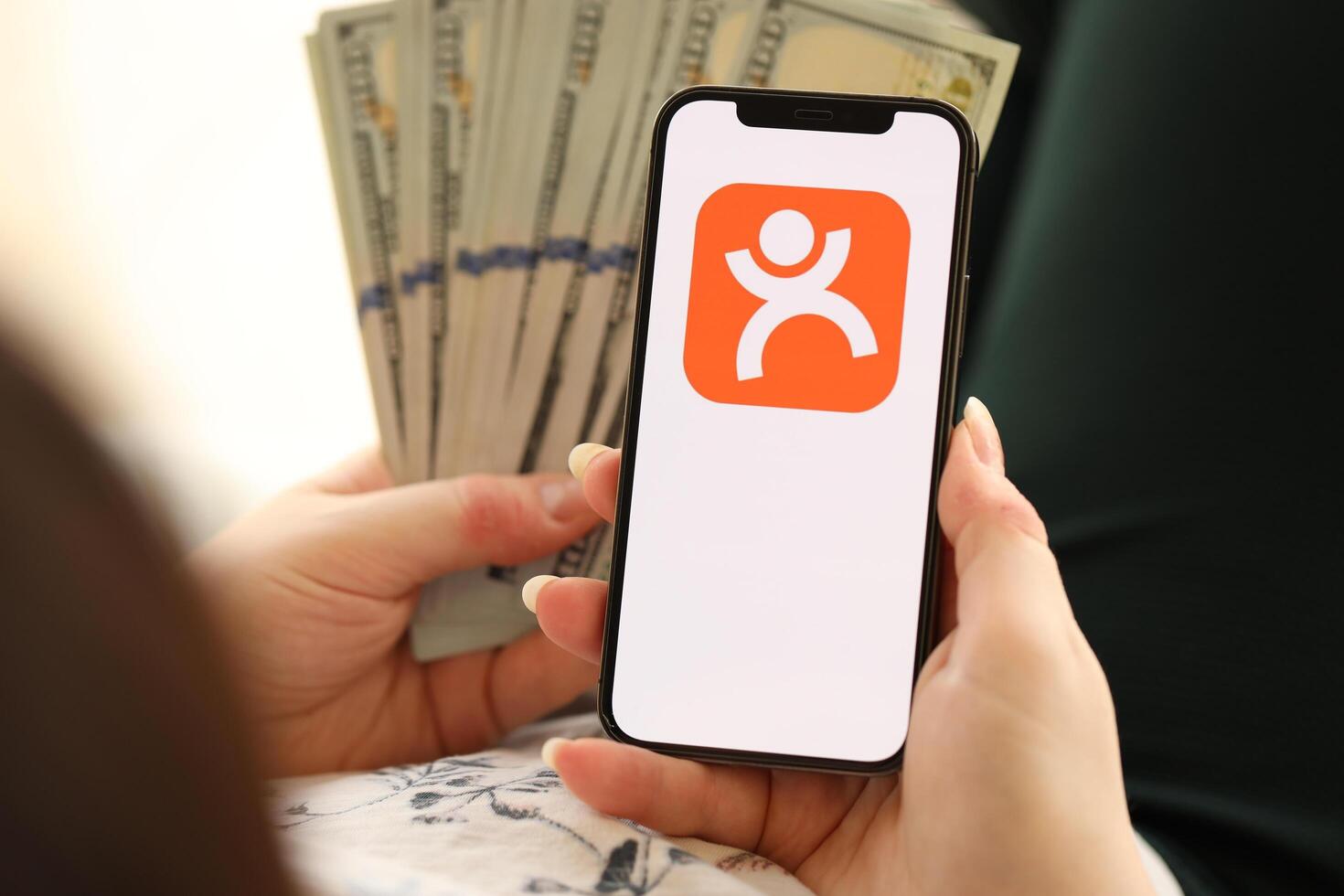 KYIV, UKRAINE - APRIL 1, 2024 Dianping platform icon on smartphone screen and money in female hand photo