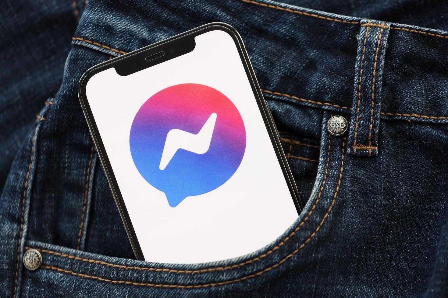 KYIV, UKRAINE - APRIL 1, 2024 Facebook Messenger icon on smartphone display screen in jeans pocket photo