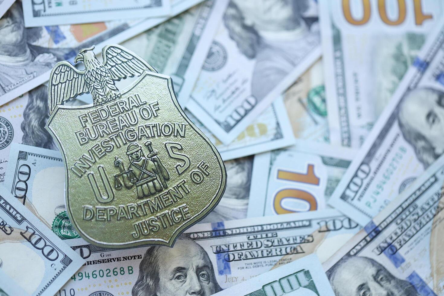 KYIV, UKRAINE - MARCH 9, 2024 US FBI Federal Bureau of Investigation badge on many US hundred dollar bills photo