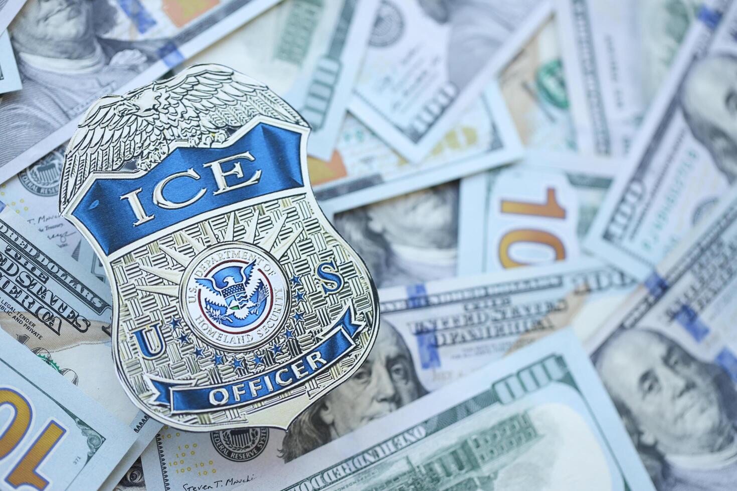 KYIV, UKRAINE - MARCH 9, 2024 US ICE Officer badge on many US hundred dollar bills photo