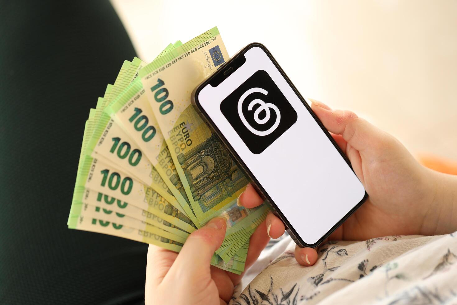 KYIV, UKRAINE - APRIL 1, 2024 Threads icon on smartphone screen and money in female hand photo