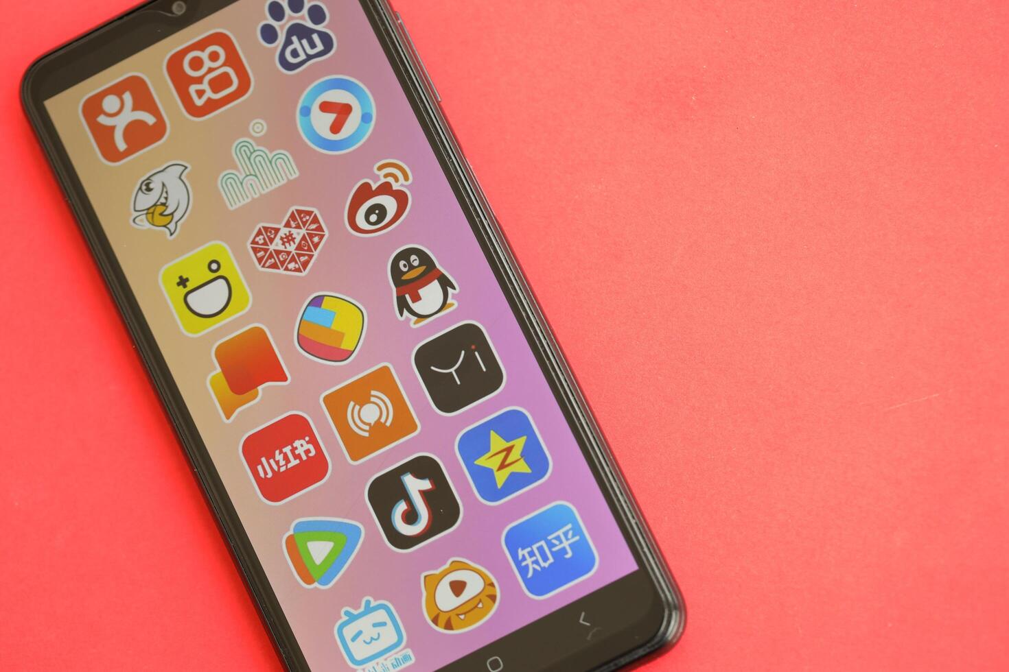 KYIV, UKRAINE - APRIL 1, 2024 Asian apps icon on smartphone screen on red table photo