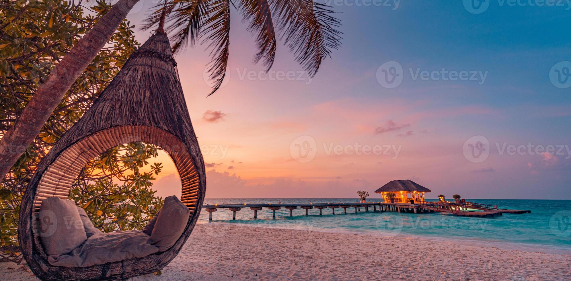 Tropical sunset beach background, summer island landscape with beach swing or hammock and sand romantic sea beach. Beautiful beach scene vacation or summer holiday concept. Honeymoon, romance resort photo