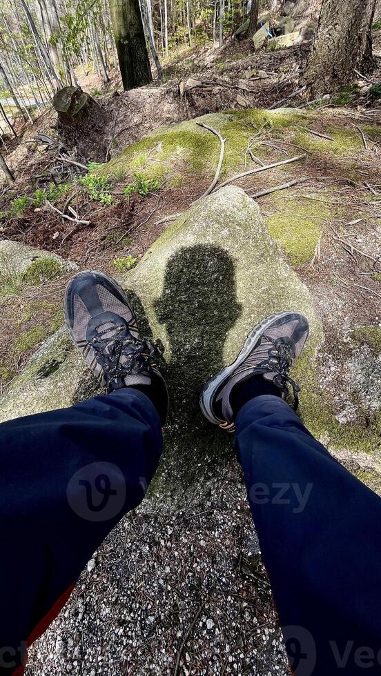 Male legs shod in sneakers and the shadow of the head falling between the legs. Tourism concept photo