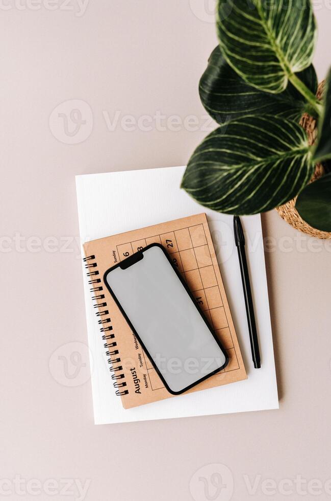 Blank path screen mobile phone with mockup on various notepads on beige background. photo