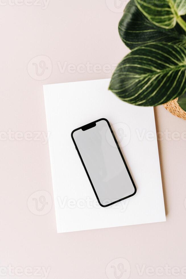 Blank path screen mobile phone with mockup on various notepads on beige background. photo