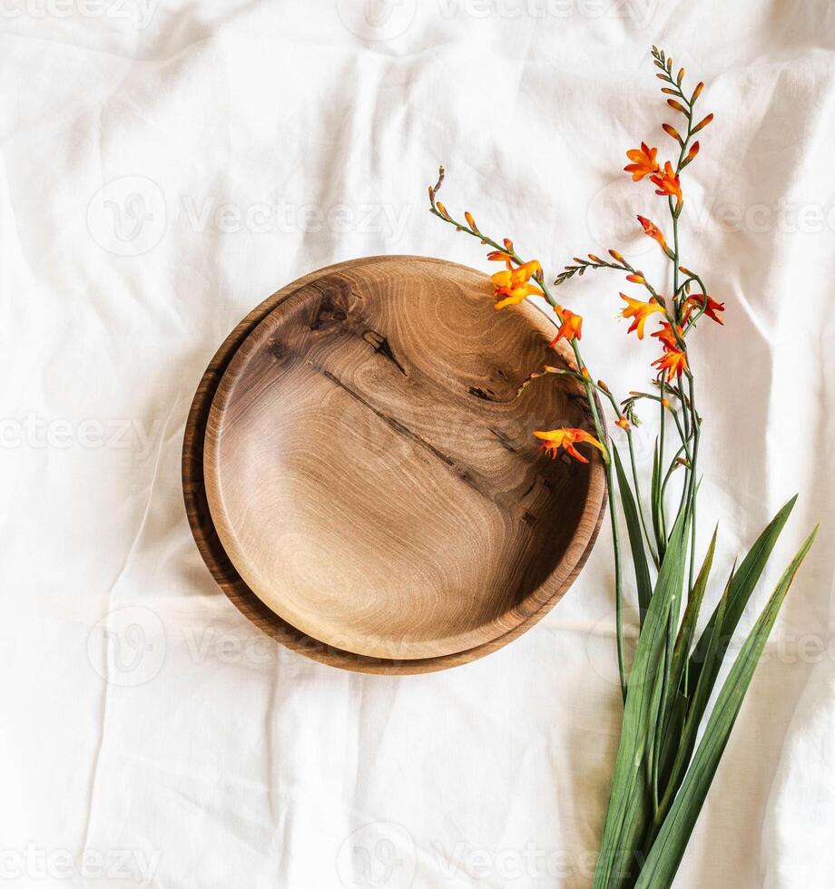 Top view of empty brown round handmade wooden bowls and orange flowers on white cotton tablecloth. Flat lay. copy sapce photo