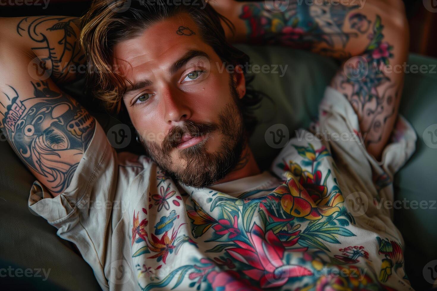 Tattooed man hipster resting on couch with floral shirt photo