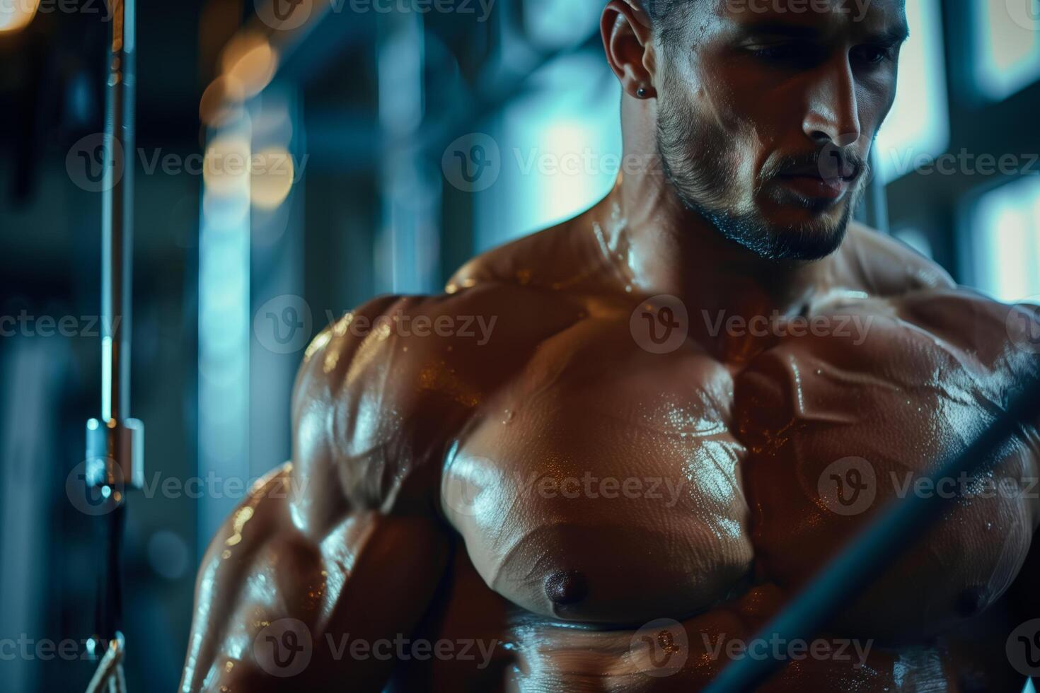 A muscular bodybuilder poses during a workout in a gym. He is flexing his chest muscles, and his body is glistening with sweat photo
