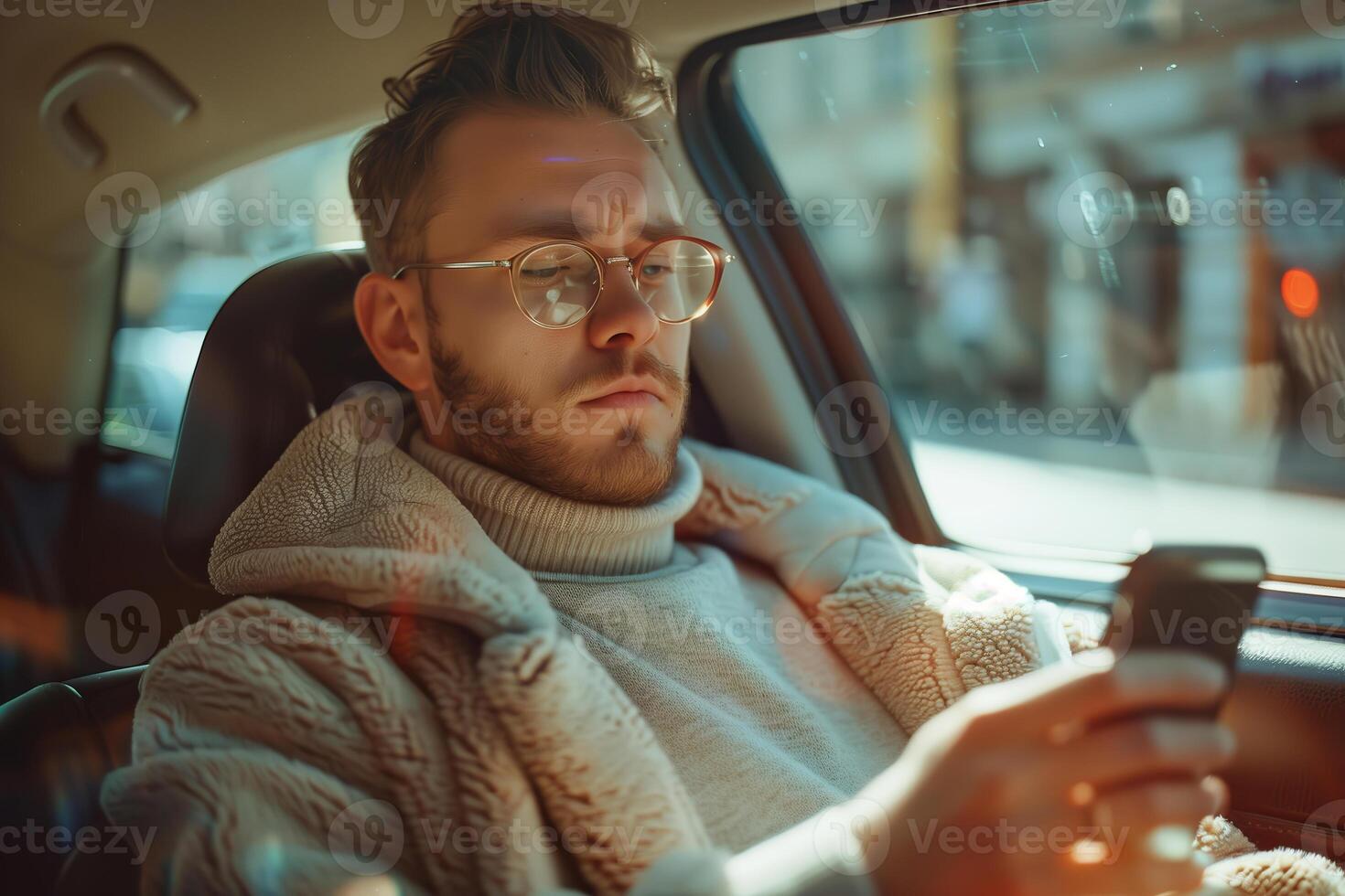Young man using smartphone while riding in a car on a sunny day photo