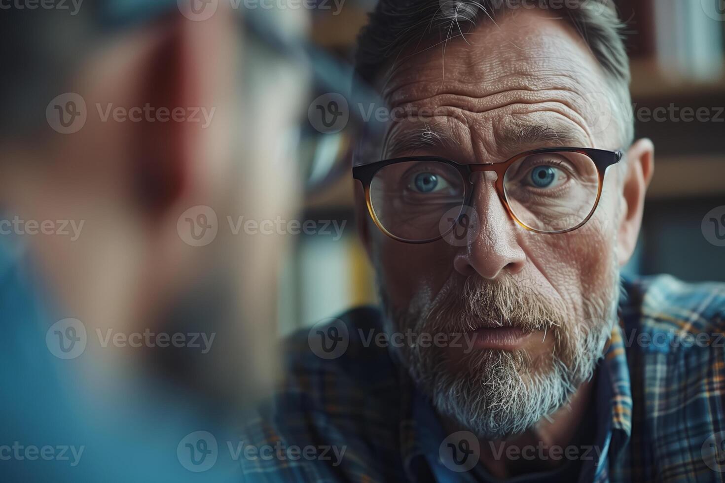 A close up portrait of a man with a white beard and glasses, looking intently at someone off-screen photo