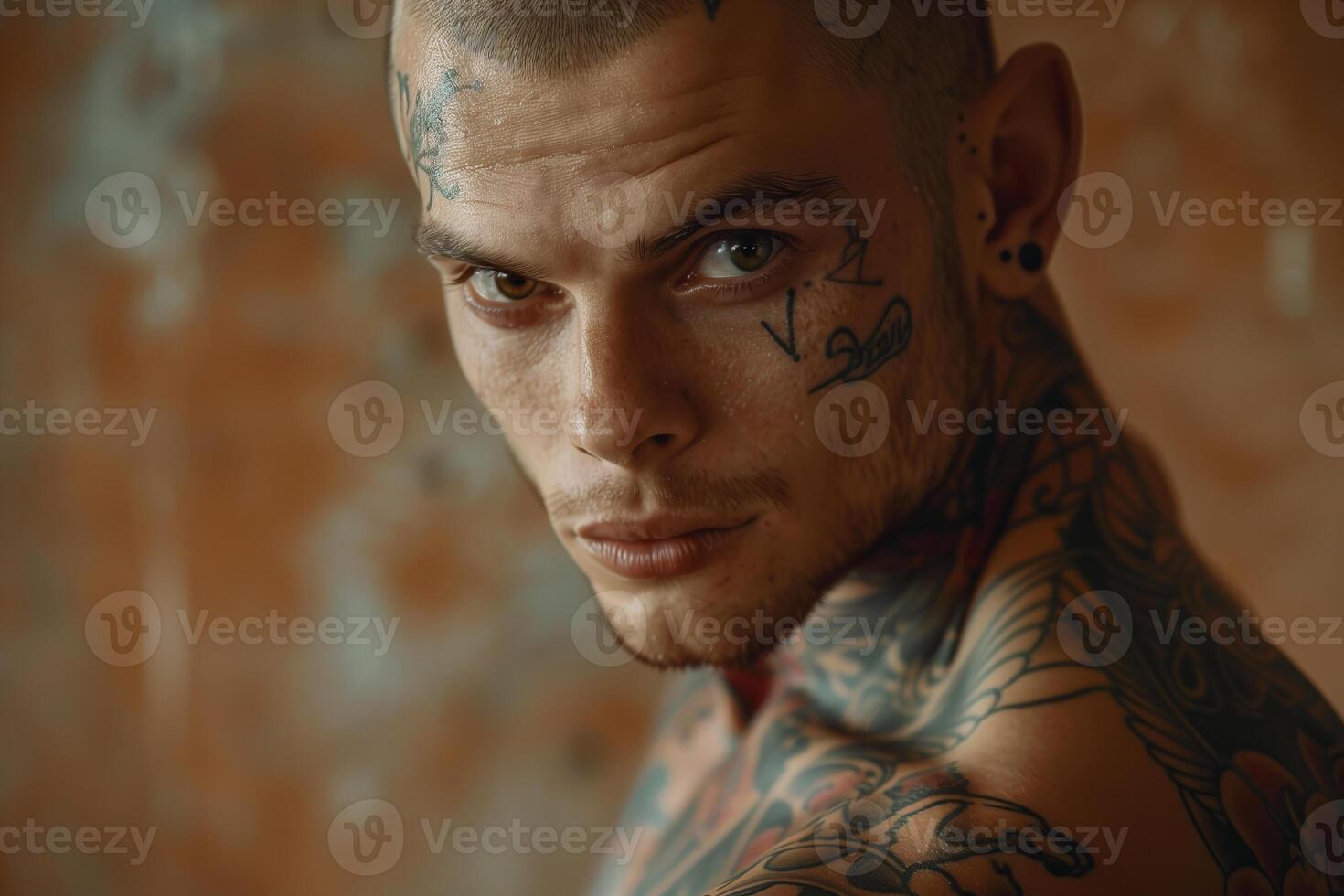 Portrait of a tattooed man with piercings looking directly at the camera photo