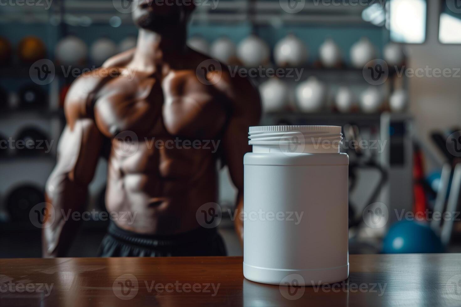 A muscular male athlete stands in a gym setting with a large container of sports nutrition supplements in the foreground. The athlete is shirtless and appears to be focused on his training photo
