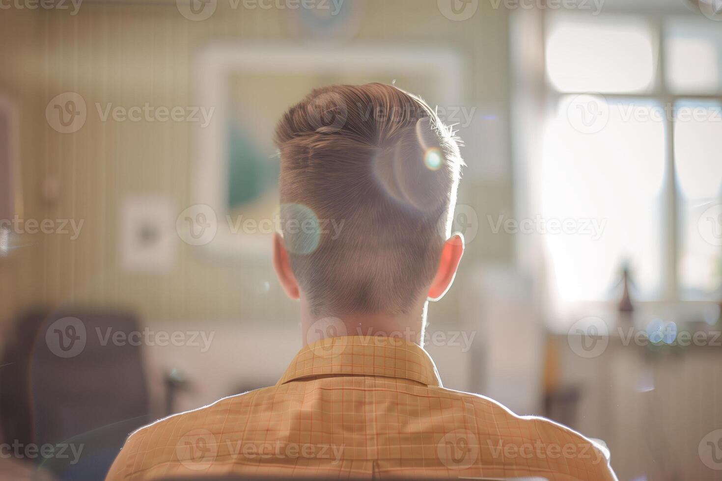Man sitting in a room looking out a window, view of the back photo