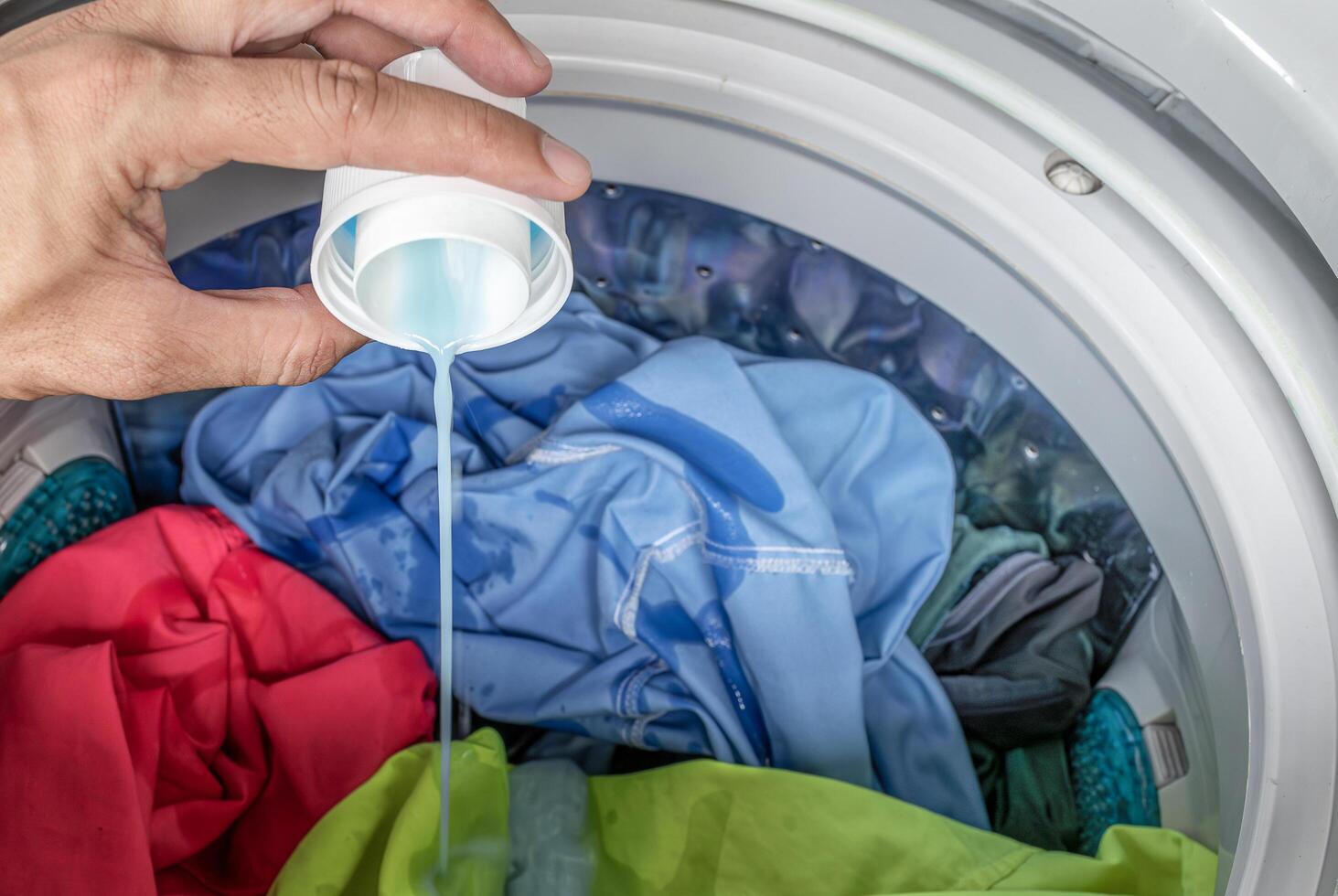 Pour laundry detergent with colorful clothes in washing machine photo
