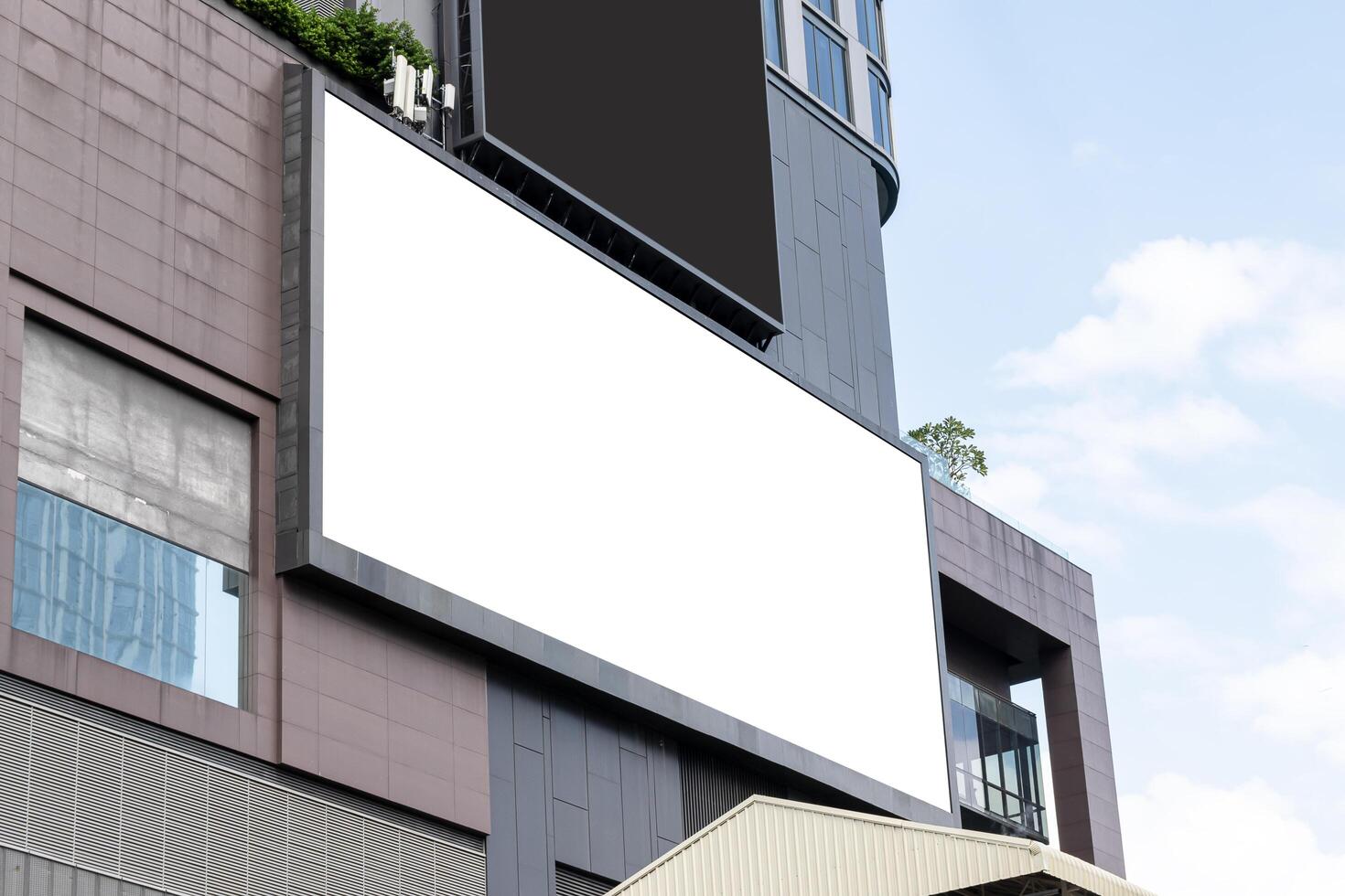 Mock up white large horizontal LED display billboard on tower building with blue sky background .clipping path for mockup photo