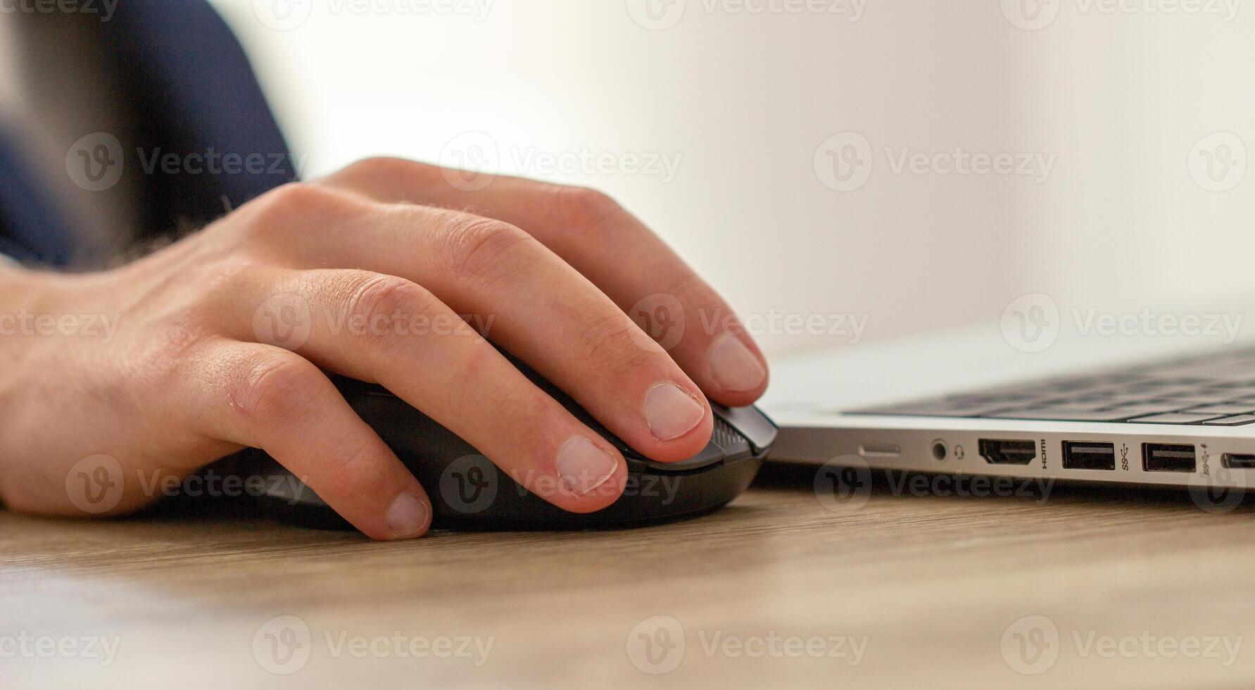 male hand on a computer mouse, workplace with laptop photo