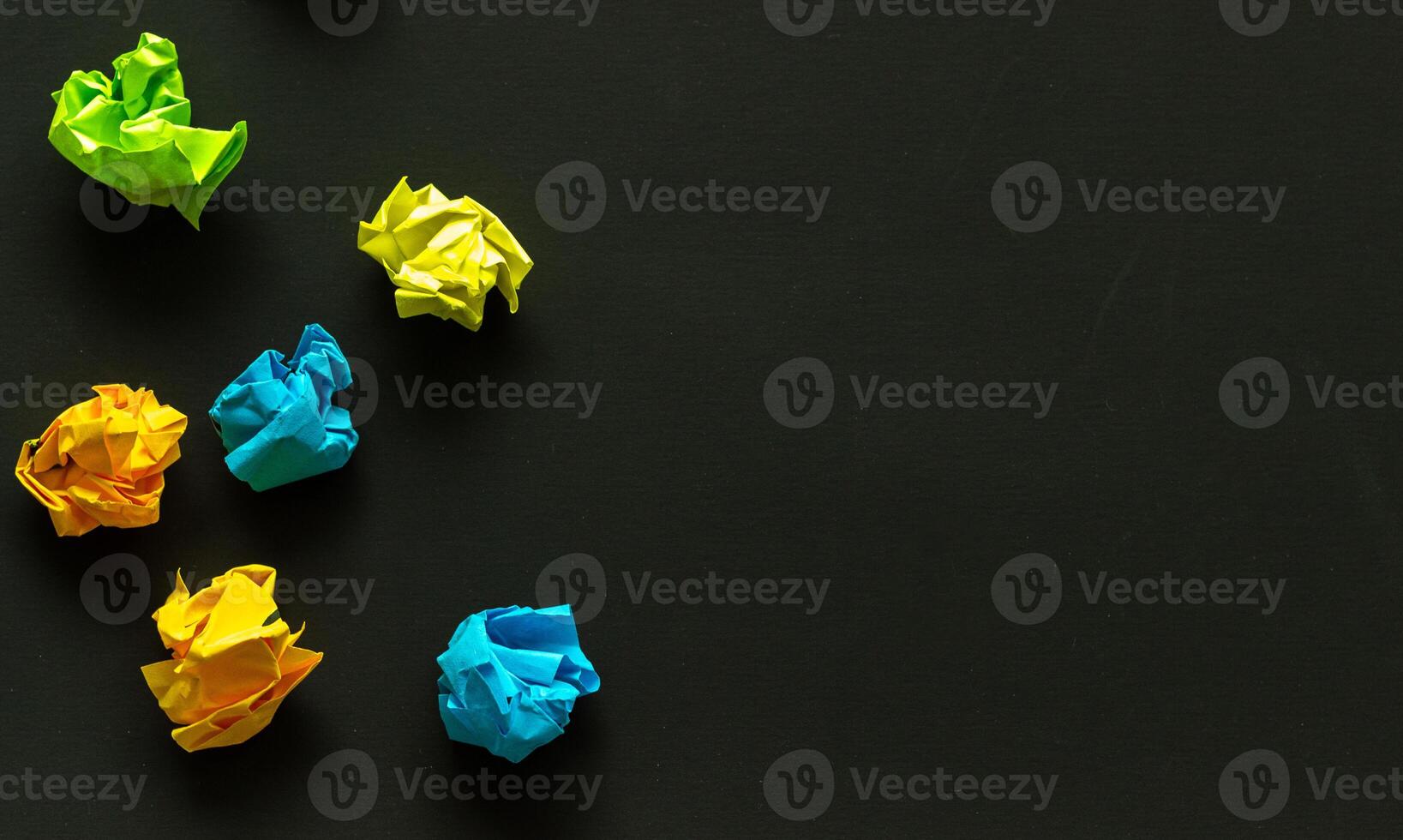 crumpled sheets of colored paper on a dark background, failed attempts, motivation concept photo