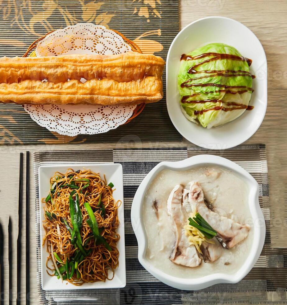 Fried dough sticks, stir fried cabbage, Fried noodles, chicken porridge served in dish isolated on napkin top view of chinese food photo
