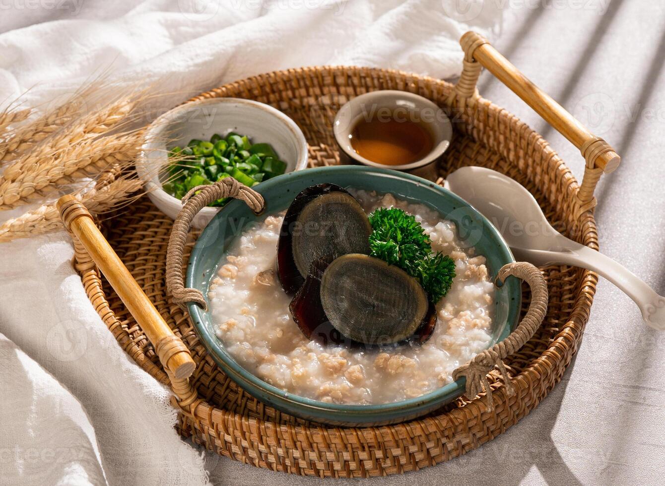 Congee century egg with pork congee with spring onion in a dish side view on grey background photo