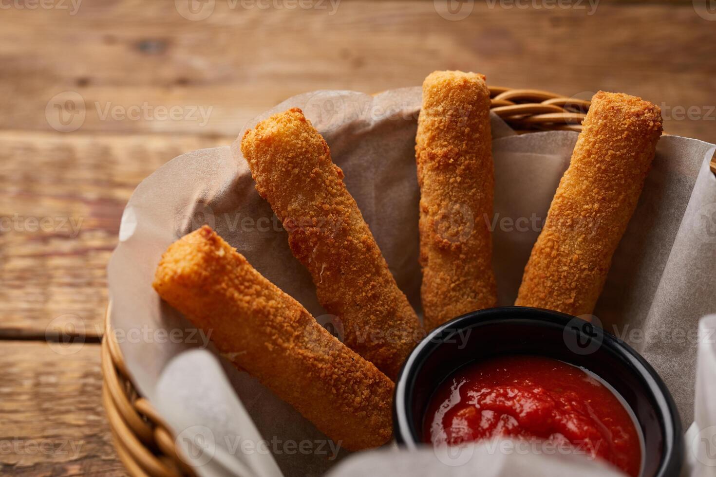 Mozzarella Sticks with ketchup dip served in a basket side view on dark background photo
