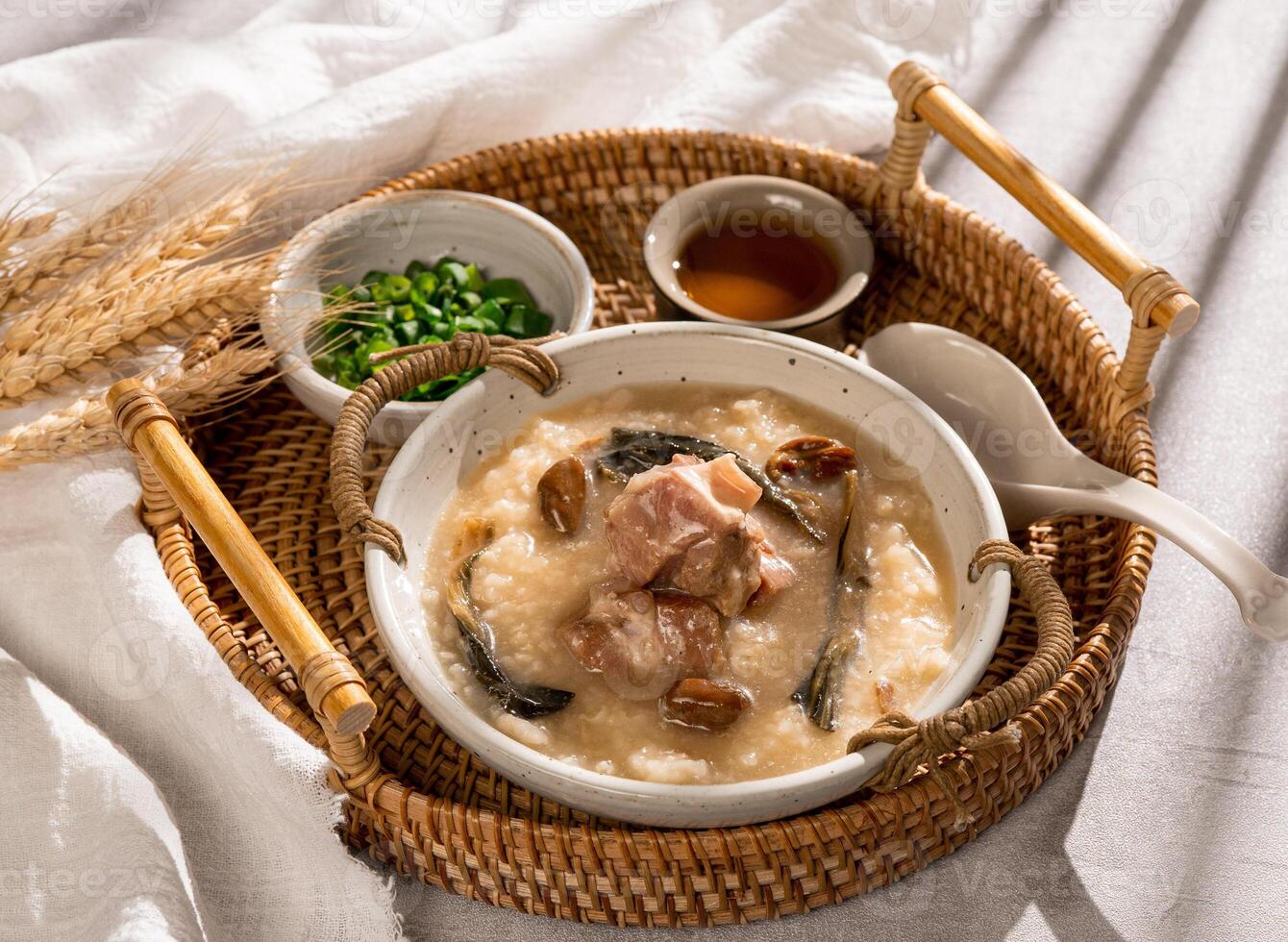 Congee pork bone congee with spring onion in a dish side view on grey background photo