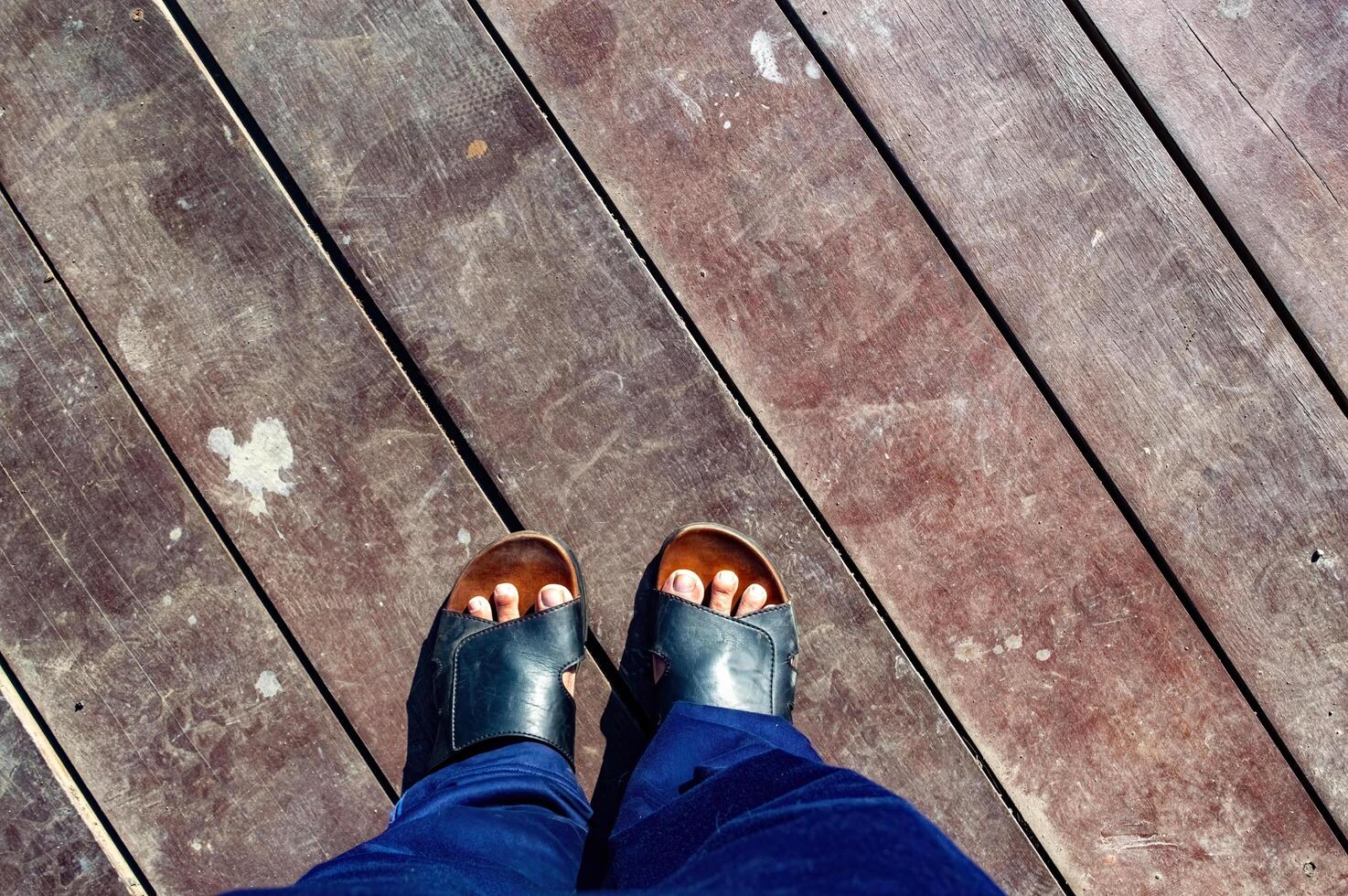 Standing on vintage gray wooden board floor. Looking down on the feet. wearing sandal. photo