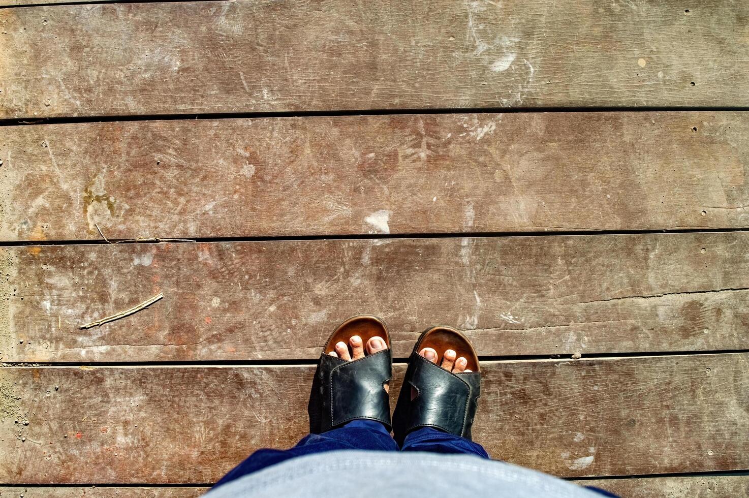 Standing on vintage gray wooden board floor. Looking down on the feet. wearing sandal. photo