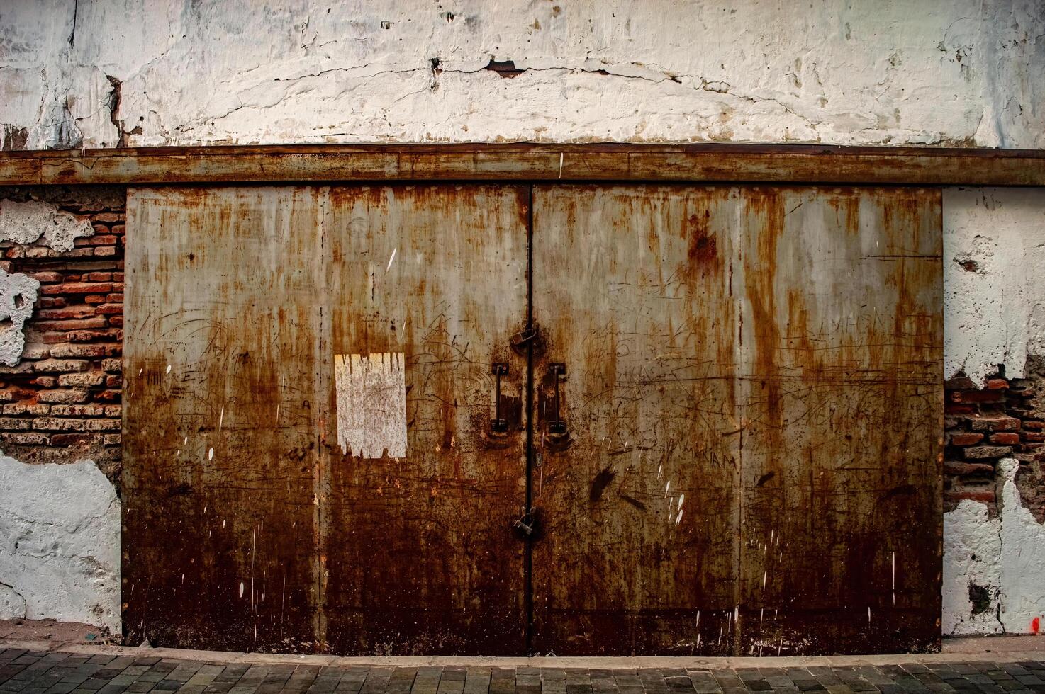 an old rusty iron warehouse door or gate on a fragile old brick wall photo