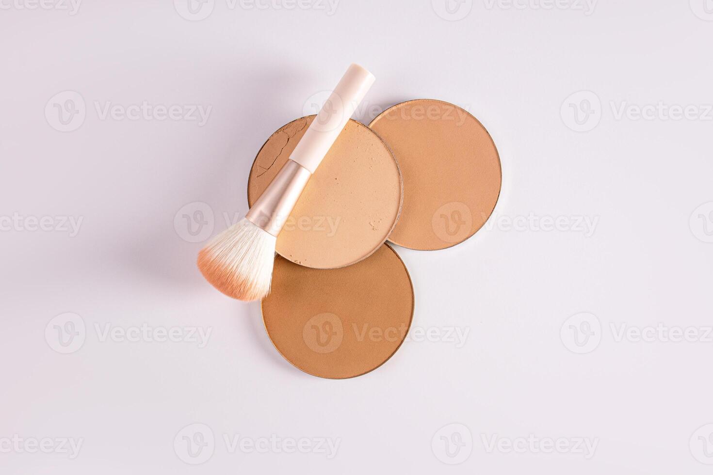 A top view of three blocks of compact powder in different tones and a delicate brush for makeup. white background. Layout for product presentation. photo