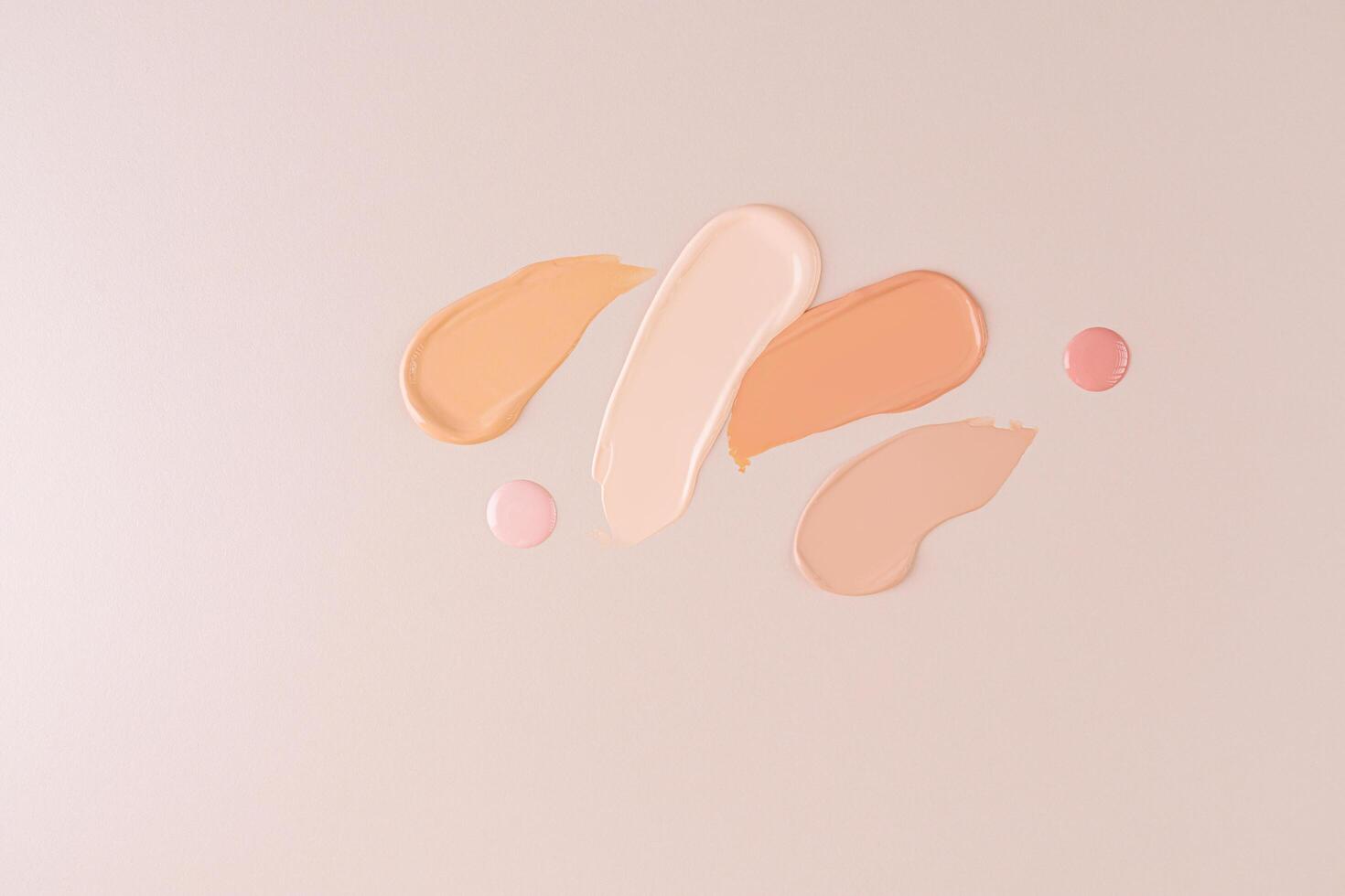 samples of liquid foundation powder in different tones and two round drops of cream on a beige background. top view. cosmetic design photo