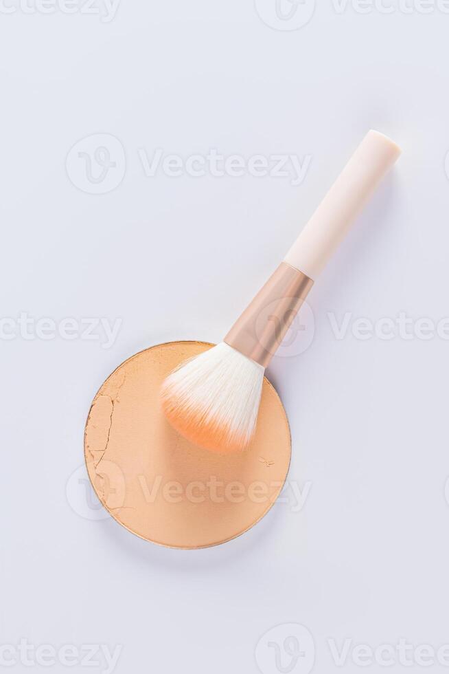 A sample of a round block of compact powder in a natural tone and a chic brush for applying makeup. vertical top view. layout for design. photo