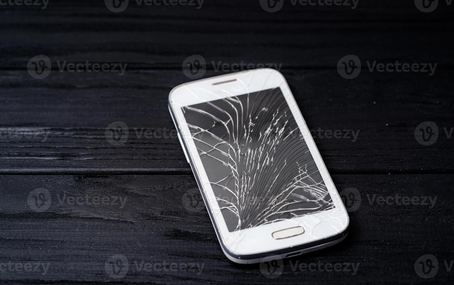 Smartphone with broken screen on dark background. Close-up. photo