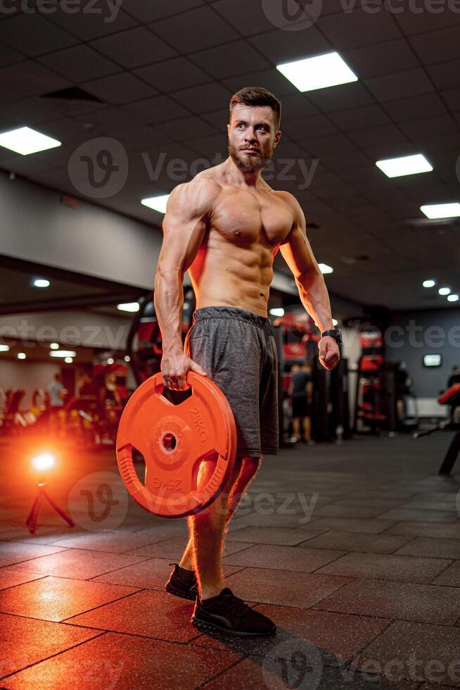 Muscular athletic training man. Strong young shirtless man working out in the gym. photo