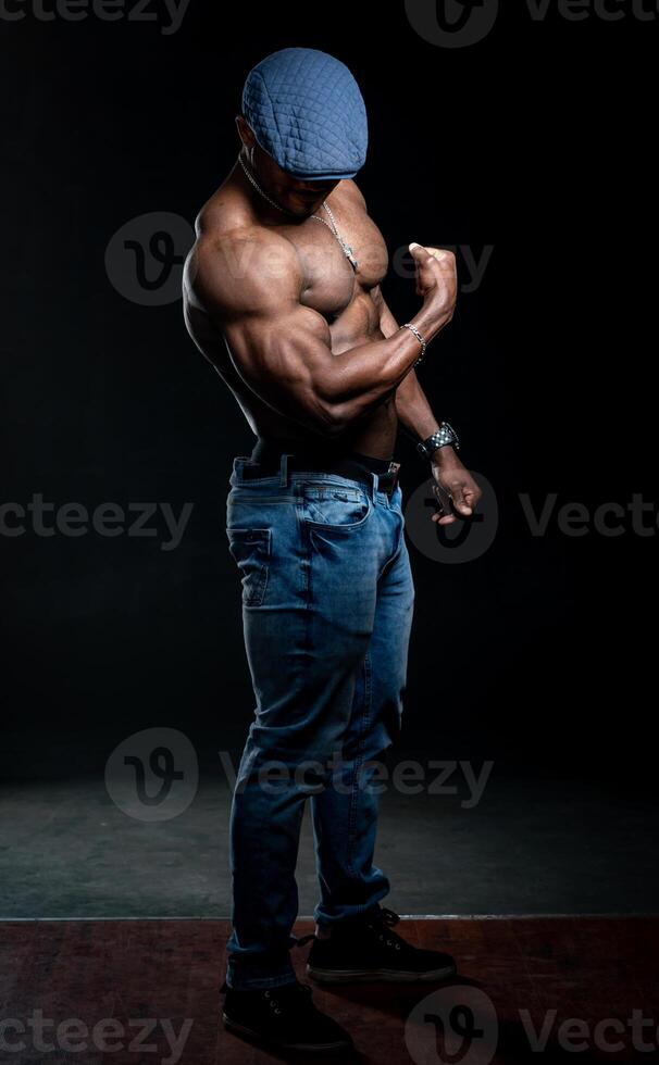 Unrecognizible man in denim cap shows perfect muscular hands to the camera. Black studio background. Full length portrait. Closeup. photo
