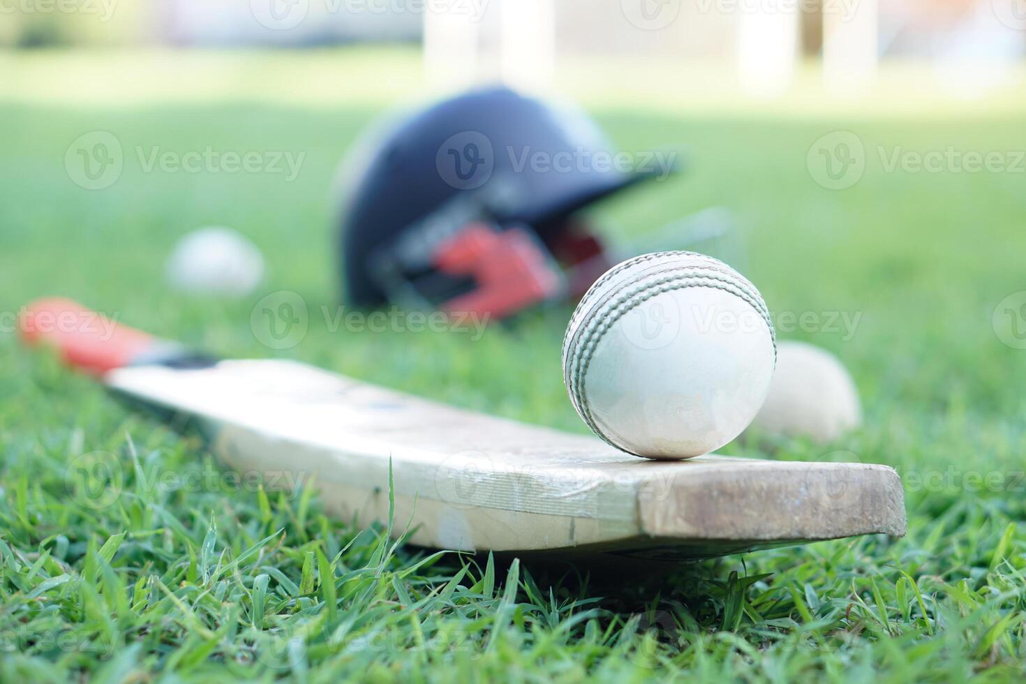White cricket ball on wooden racket. Concept, sport equipment. Competitive sport. A cricket ball is made with a core of cork, covered by a leather case with a slightly raised sewn seam photo