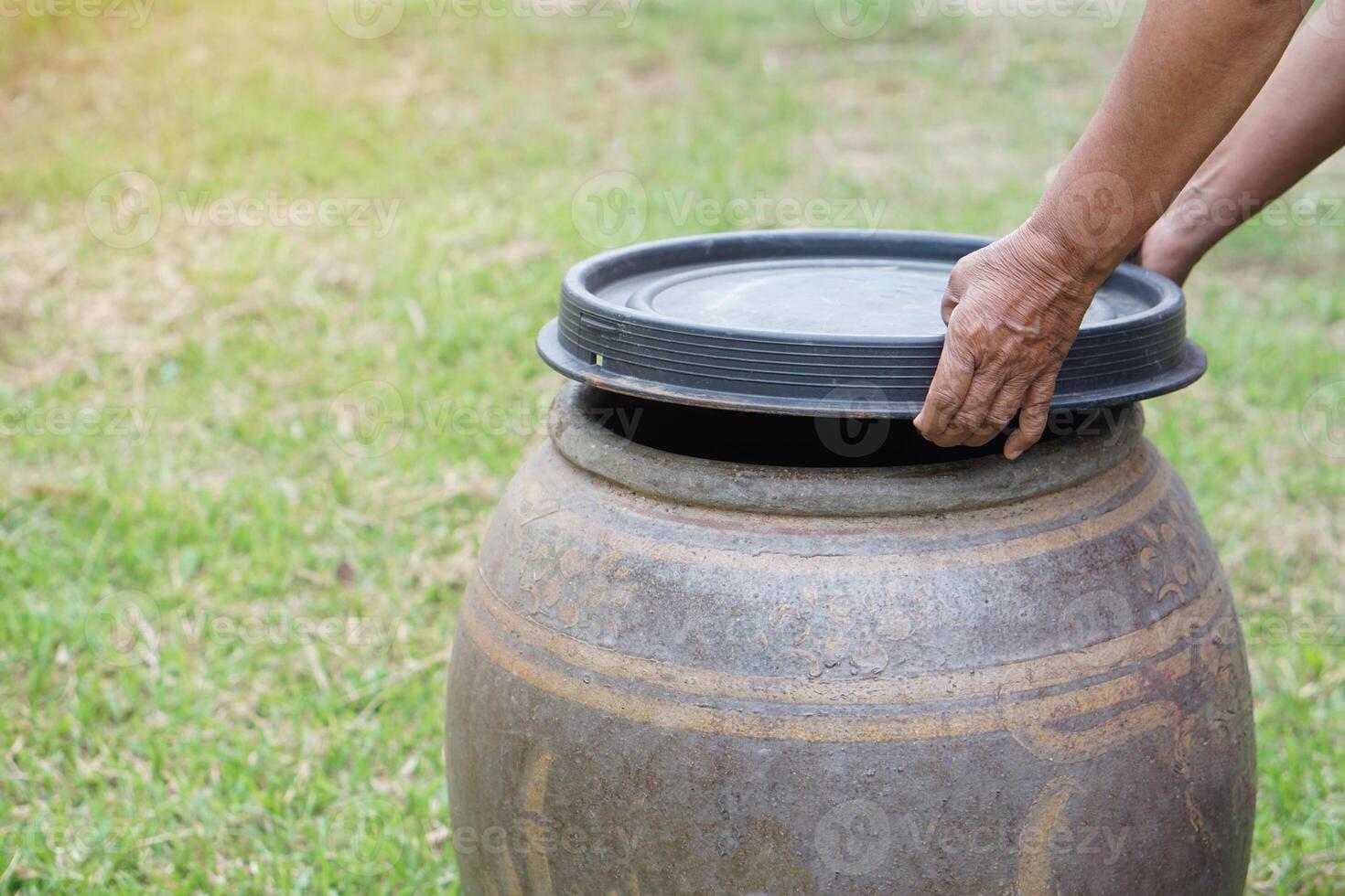 Closeup hands hold lid to cover water jar to protect from mosquitoes to breed inside or other insects or dust go into water. Concept, campaign to stop mosquitoes cycle to lay eggs in water container photo