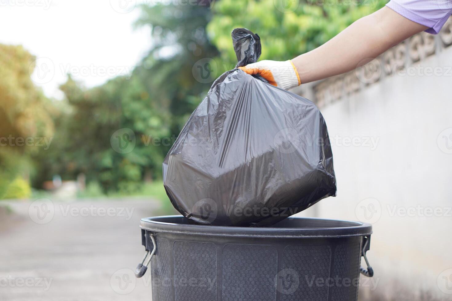 Hand holding garbage black bag putting in to the bin. Concept, garbage management, Keep clean for sanitary and community service for the best environment. Zero waste. photo